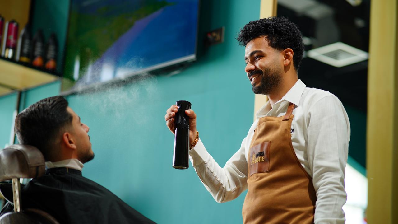A barber finishing a cut with a spray bottle