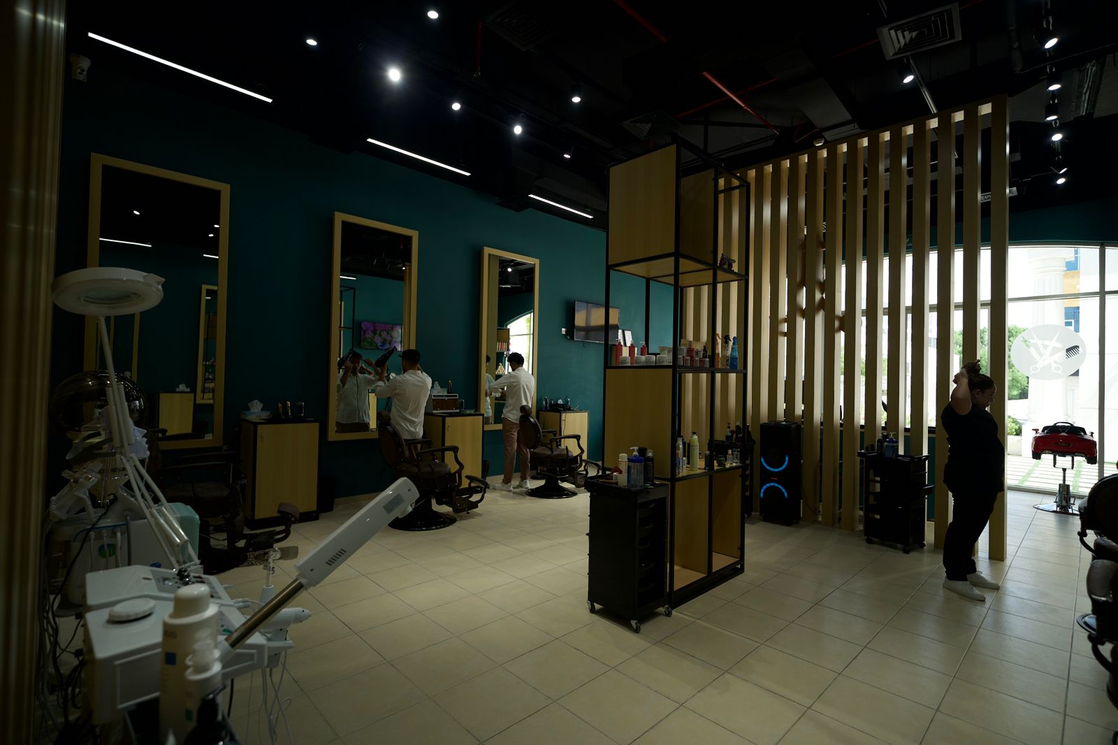 The Dubai shop floor: barber stations, mirrors and brass partitions.