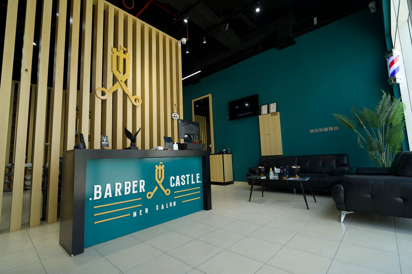 The Barber Castle reception desk in Dubai, with the brass crest, teal front and gold lettering.