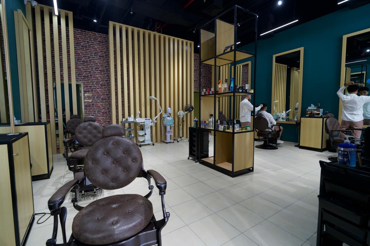 A row of brown leather barber chairs against the brass slat partitions on the Dubai shop floor.
